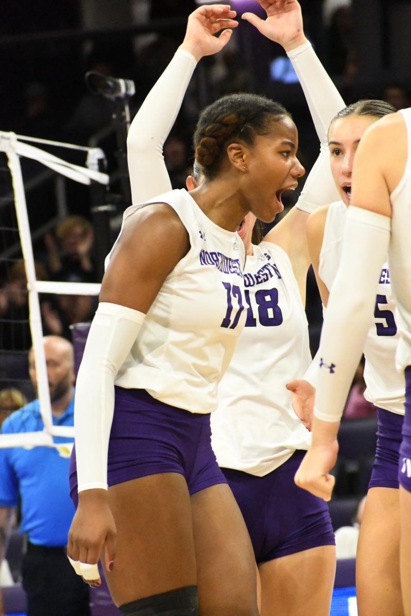 A player in a white and purple volleyball uniform celebrates.