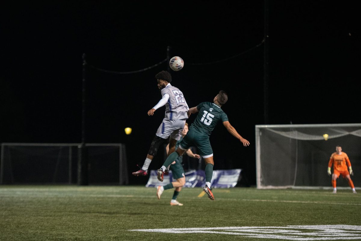 Graduate student forward Ugo Achara Jr. leaps for an aerial duel against a Spartan. Northwestern fell to Michigan State 2-1 on Friday.