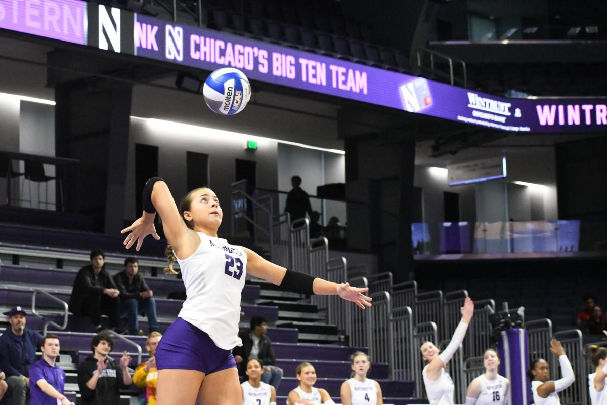 A player in a purple and white jersey jumps to hit a volleyball.