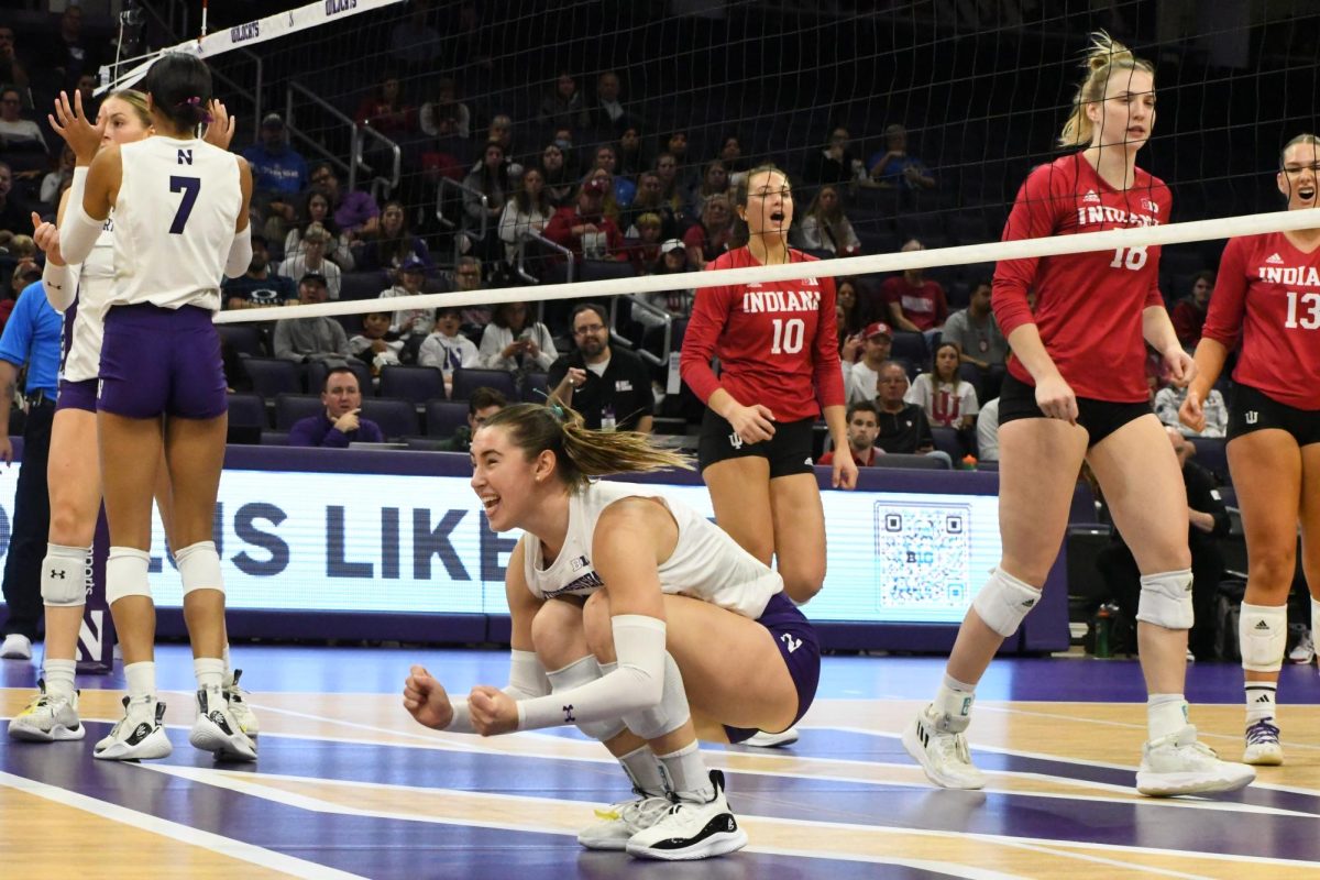 A player in a white and purple volleyball uniform crouches down while yelling in excitement.