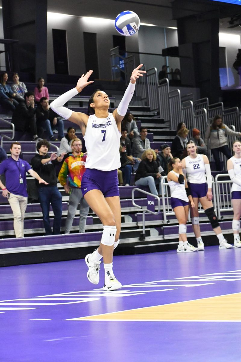 A player in a white and purple uniform prepares to serve.