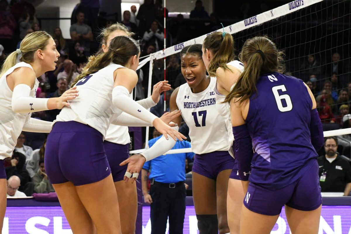 A group of players in purple and white uniforms celebrate in a huddle.