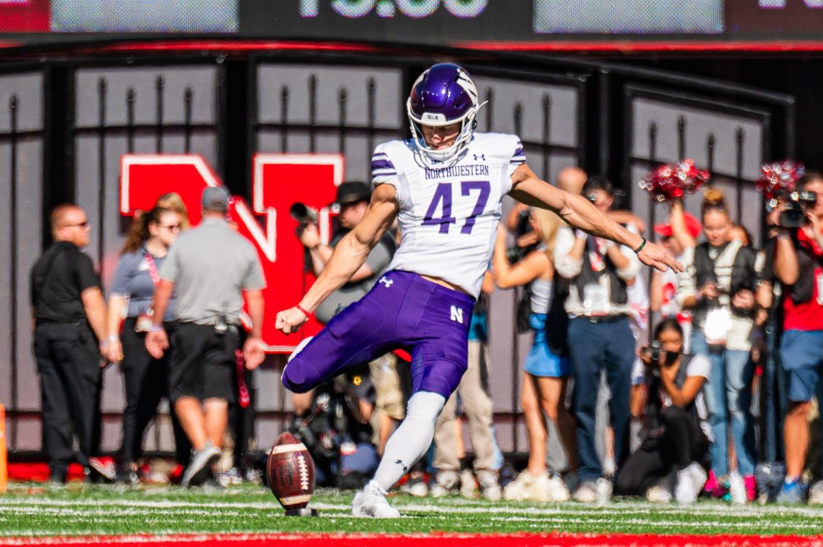 A football player in purple and white punts a ball.