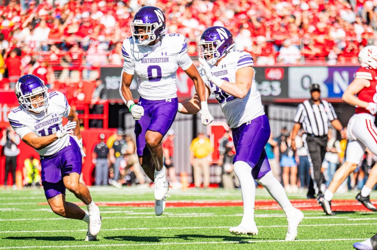 A player jumps up among other football players in purple and white, celebrating.