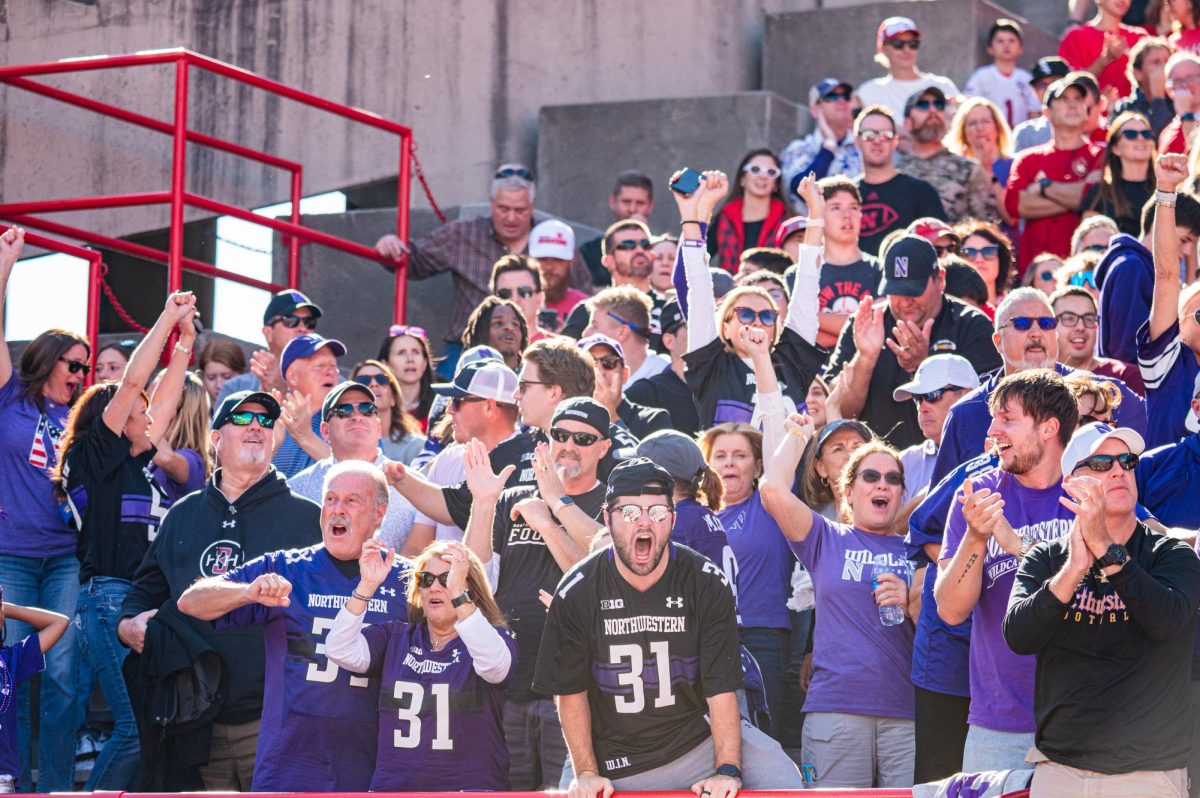 Fans in purple and black cheer from the sidelines.