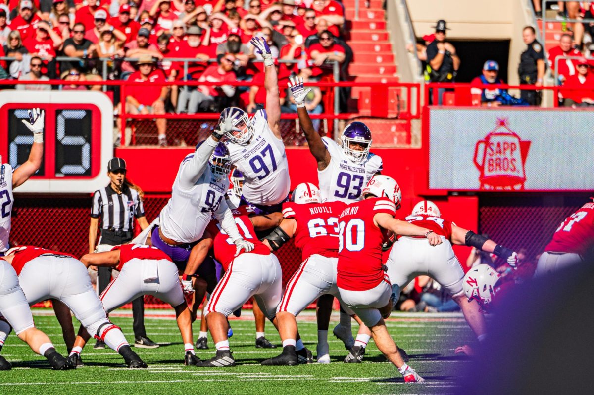 Football players in purple and white reach into the air.