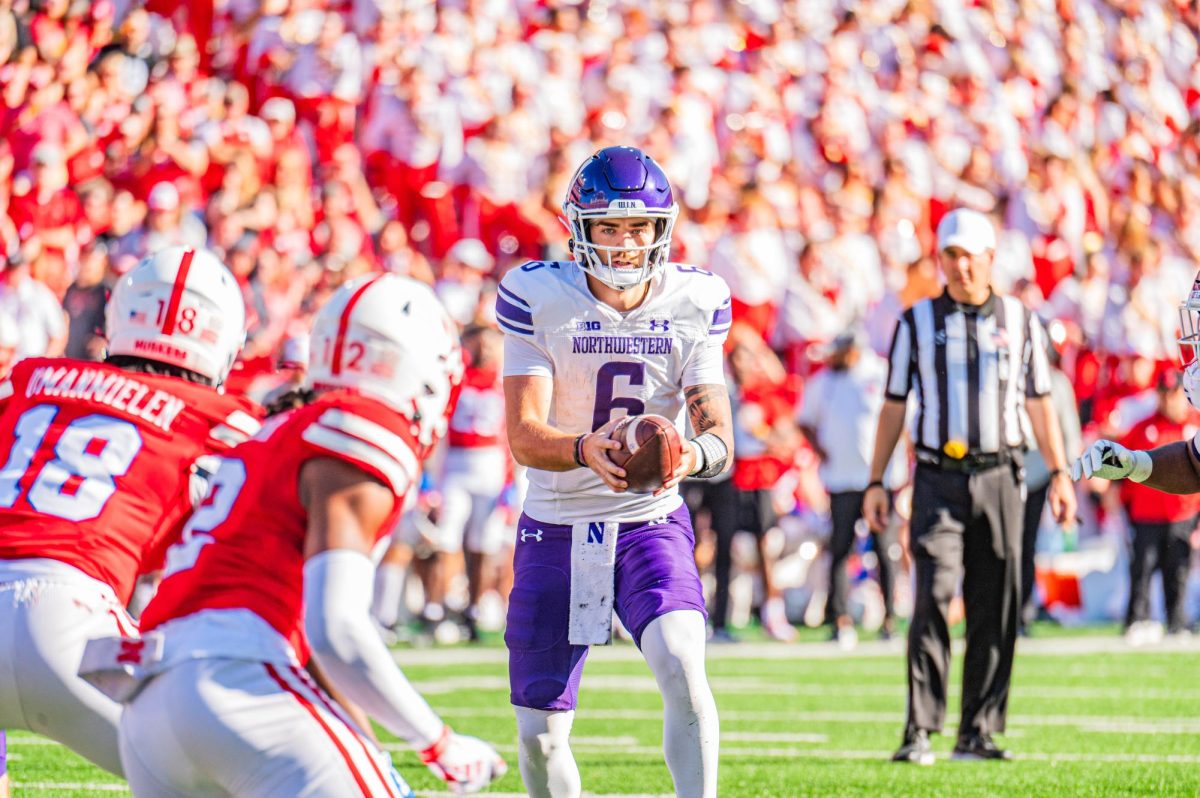 A football player in purple and white prepares to hand off a football.