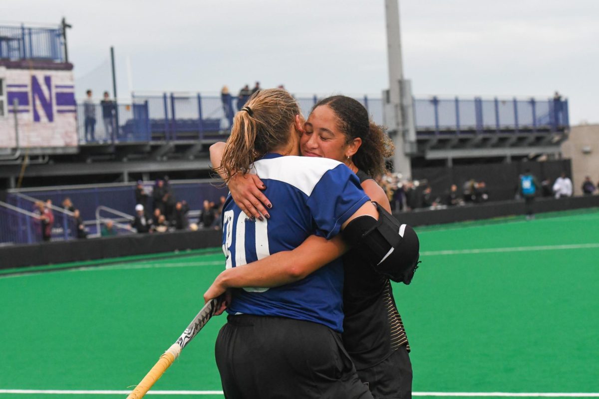 A player in a blue jersey and a player in a black jersey hug.