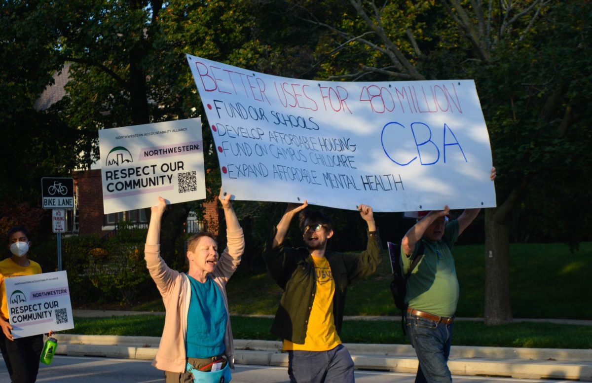Protesters hold a sign advocating for a CBA between Northwestern and Evanston at a demonstration last week. A CBA is a legally enforceable contract between a developer and community groups representing individuals impacted by the development.