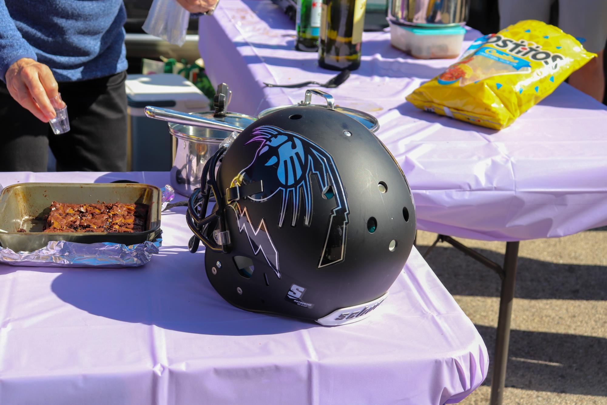 A black Northwestern helmet with a metallic wildcat decal sits on a snack table with purple tablecloth.