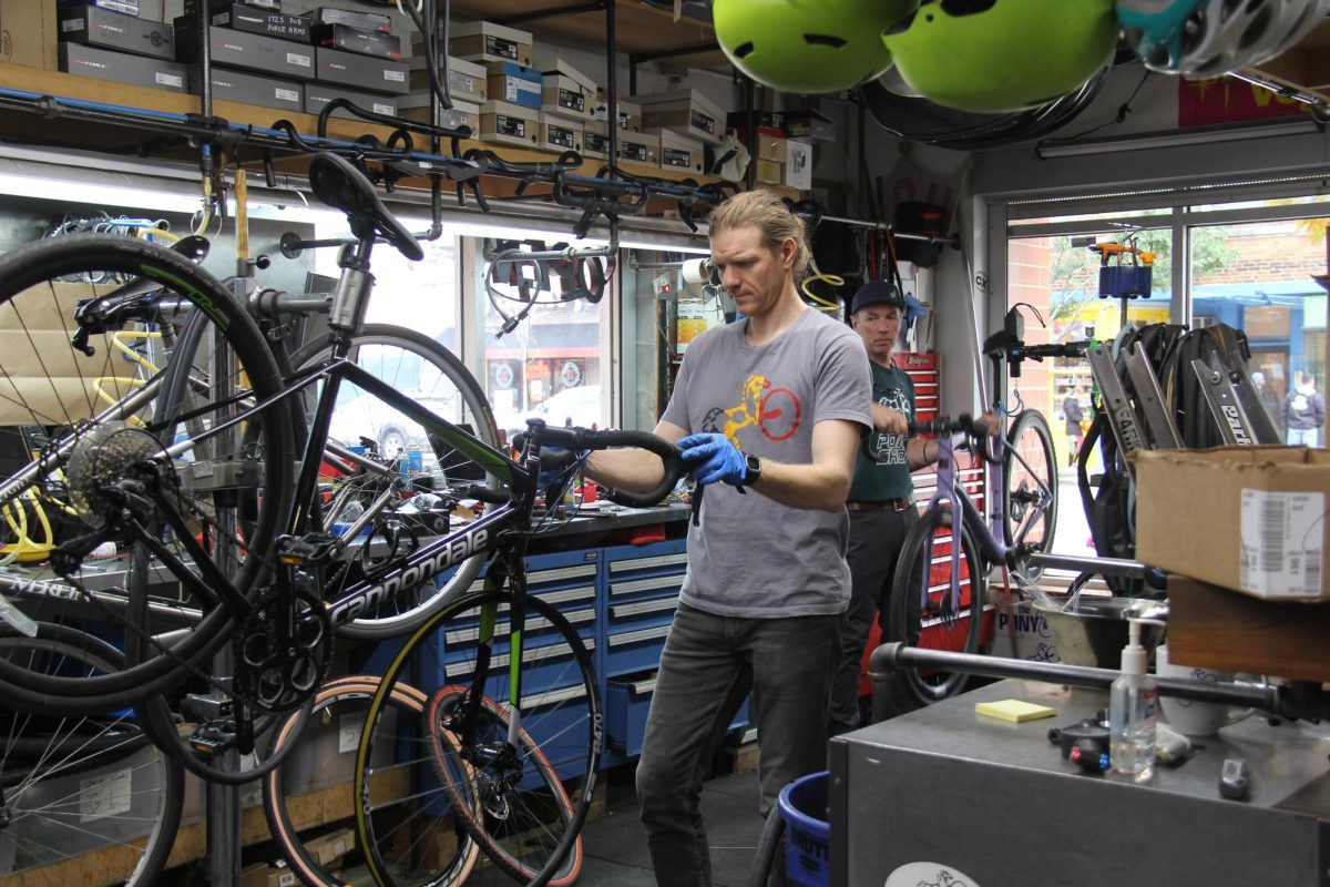 Two people repairing bikes inside a bike shop.