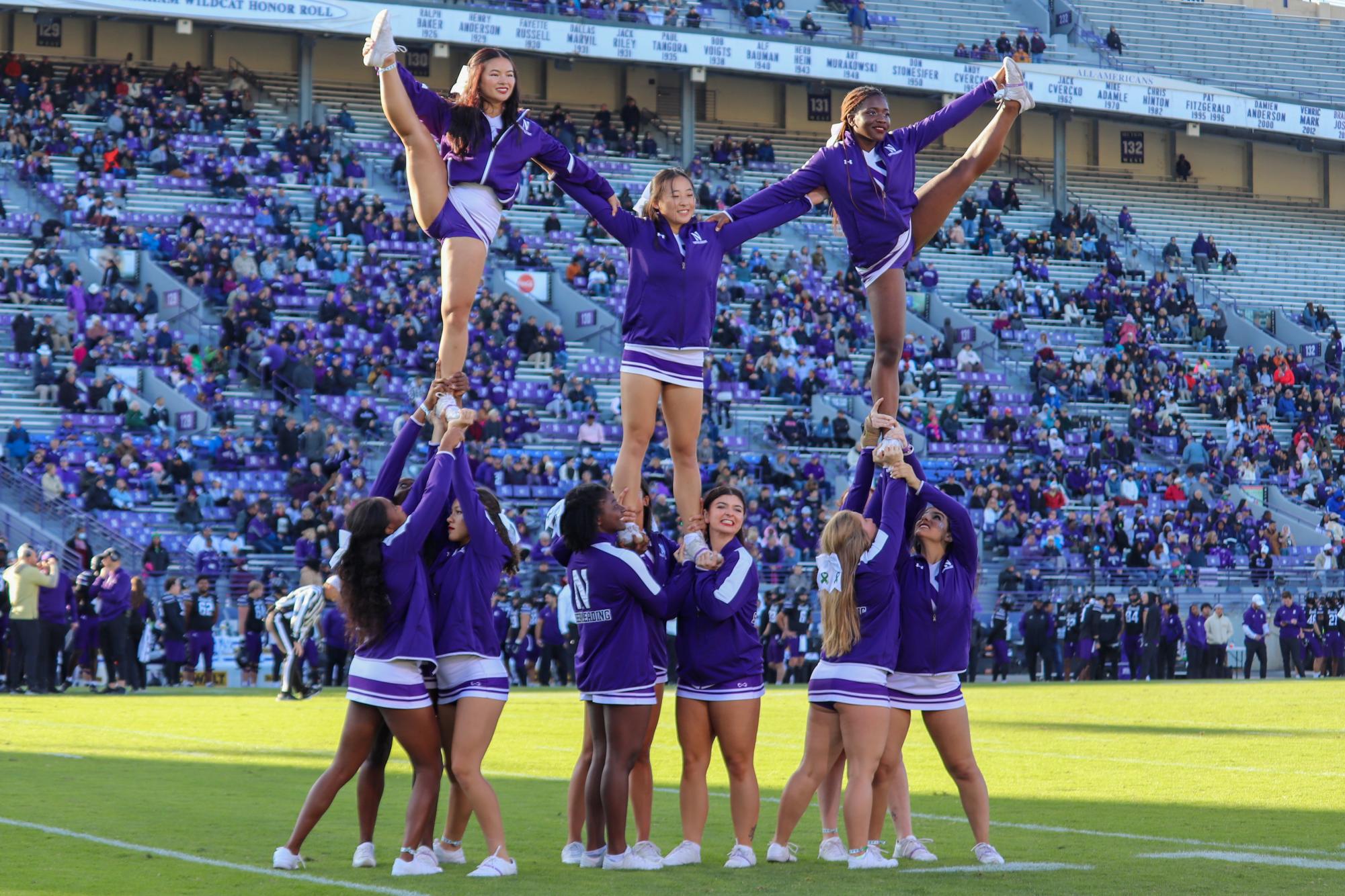 Cheerleaders dressed in purple stand in a two-level formation.