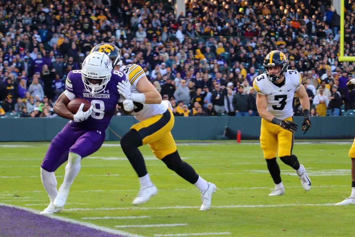 Senior wide receiver A.J. Henning is pushed out of bounds by an Iowa defender after catching a seven-yard pass from junior quarterback Brendan Sullivan in NU’s loss at Wrigley Field Saturday.
