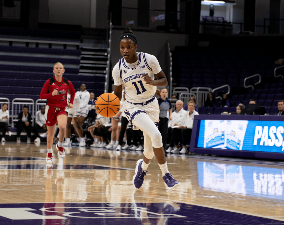 A basketball player wearing purple and white dribbles down the court while another player wearing red runs behind.