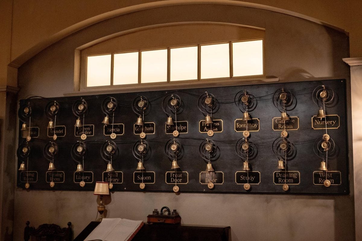 A board with two rows of bells, each with labels of different rooms attached to them.