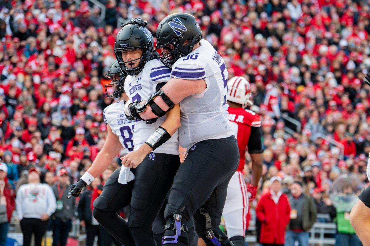 Two football players in purple and white celebrate after a play.