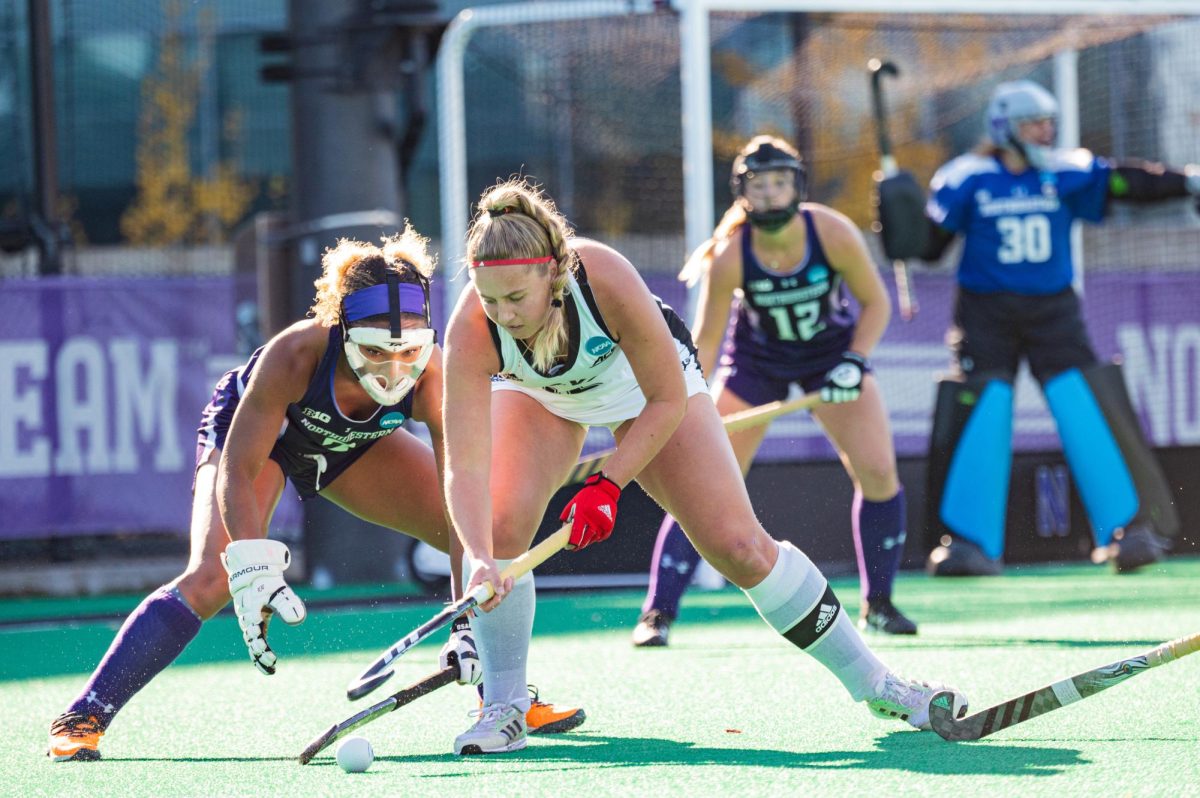 Two field hockey players vie for the ball.