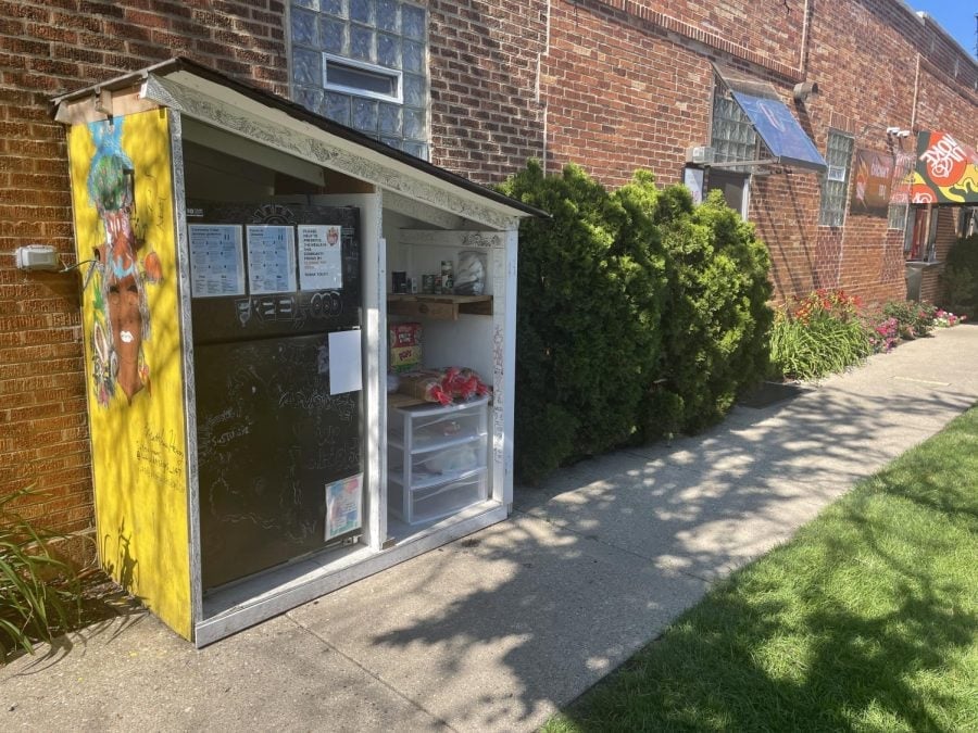 A black refrigerator and pantry under a small yellow roof on the sidewalk outside of Soul & Smoke.