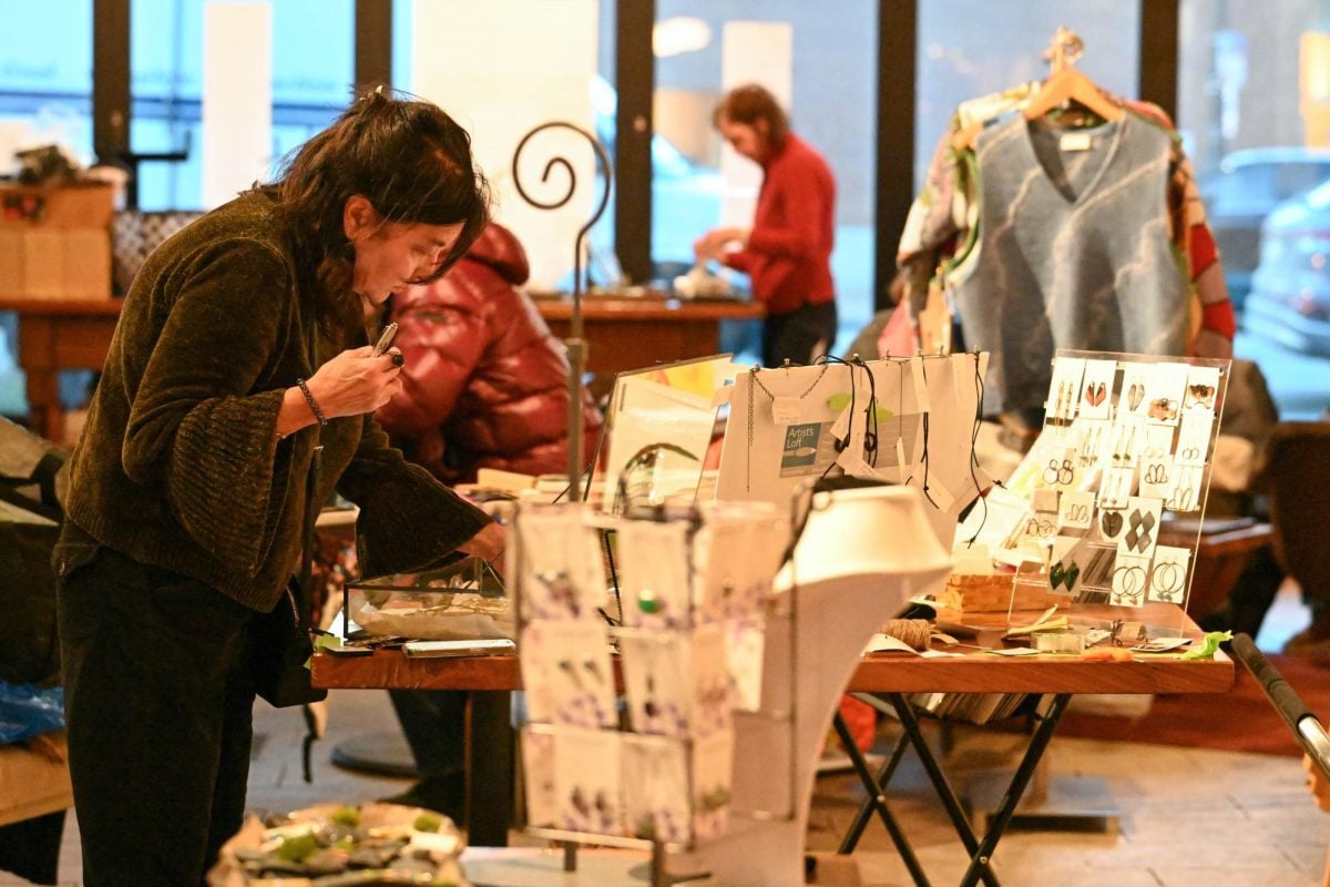 A+few+people+wearing+layers+sort+through+art+items+on+tables.