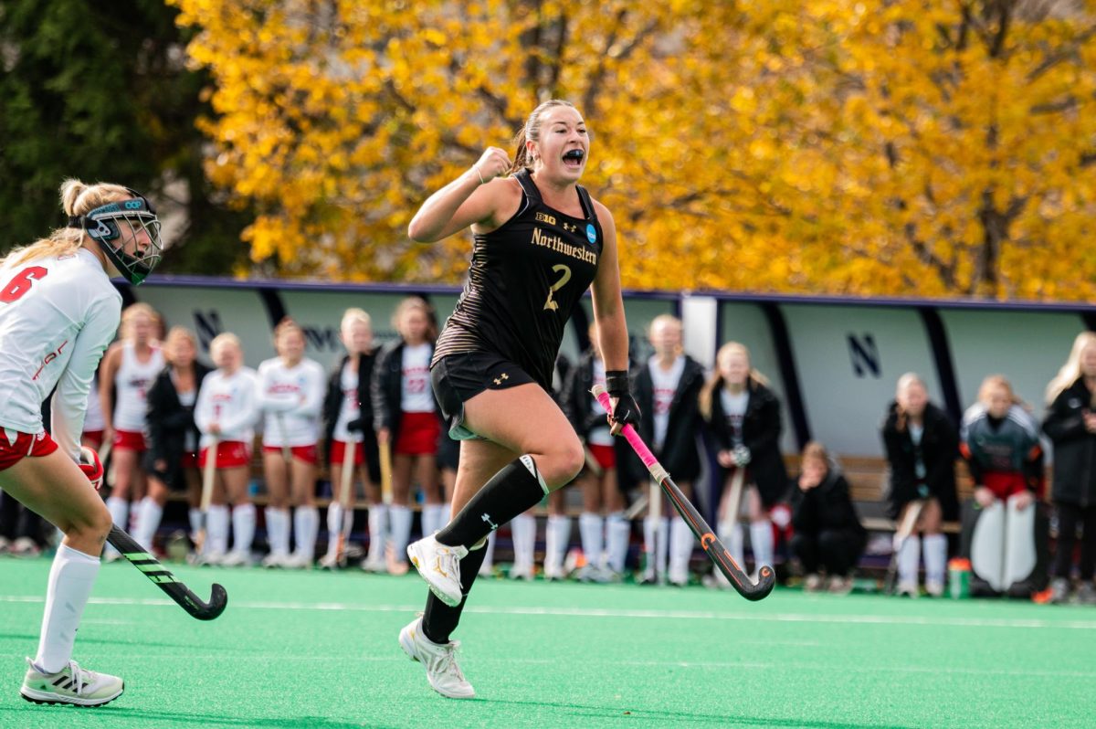 A field hockey player in black cheers.