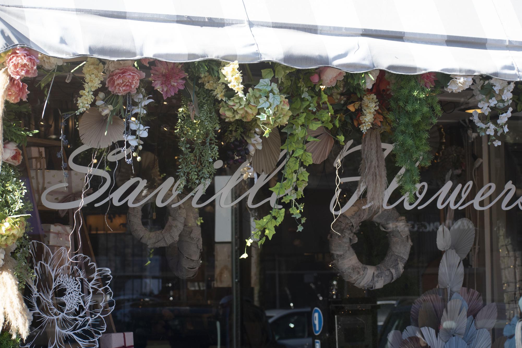 A storefront window covered in flowers with “Saville Flowers” written on it.