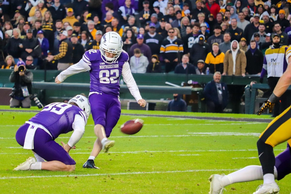 A player in purple and white kicks a football on the field.