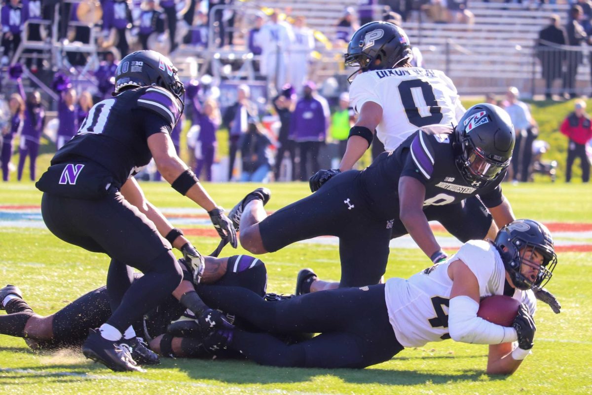 Northwestern defensive players tackle a Purdue rusher. NUs defense forced two turnovers in the Saturday win.