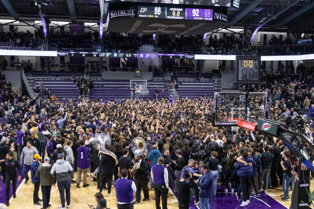 The basketball court is full of students. The scoreboard reads 92-88 with Northwestern winning the game.