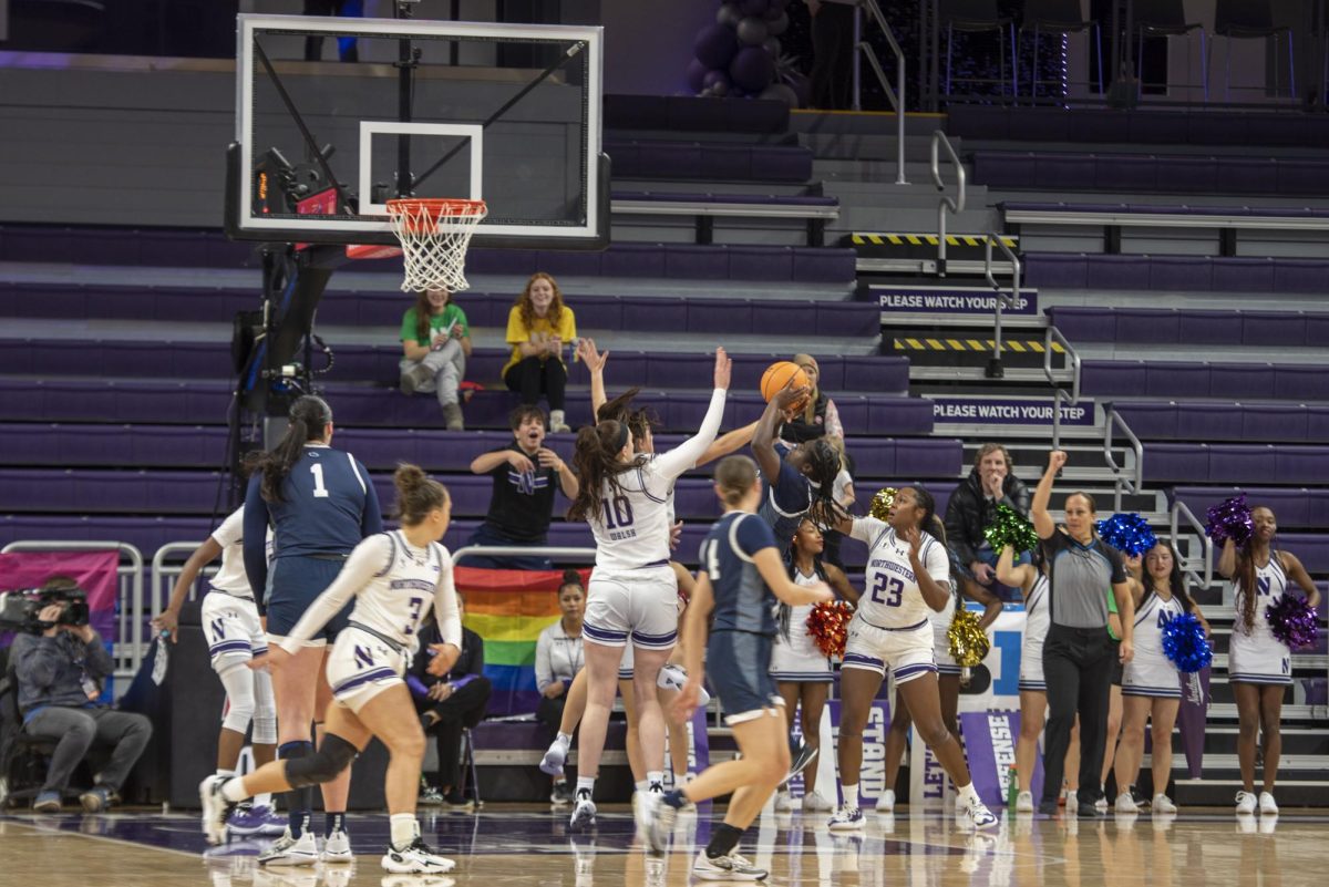 Caileigh Walsh and another Northwestern player reach to block a player in a blue jersey jumping to shoot.