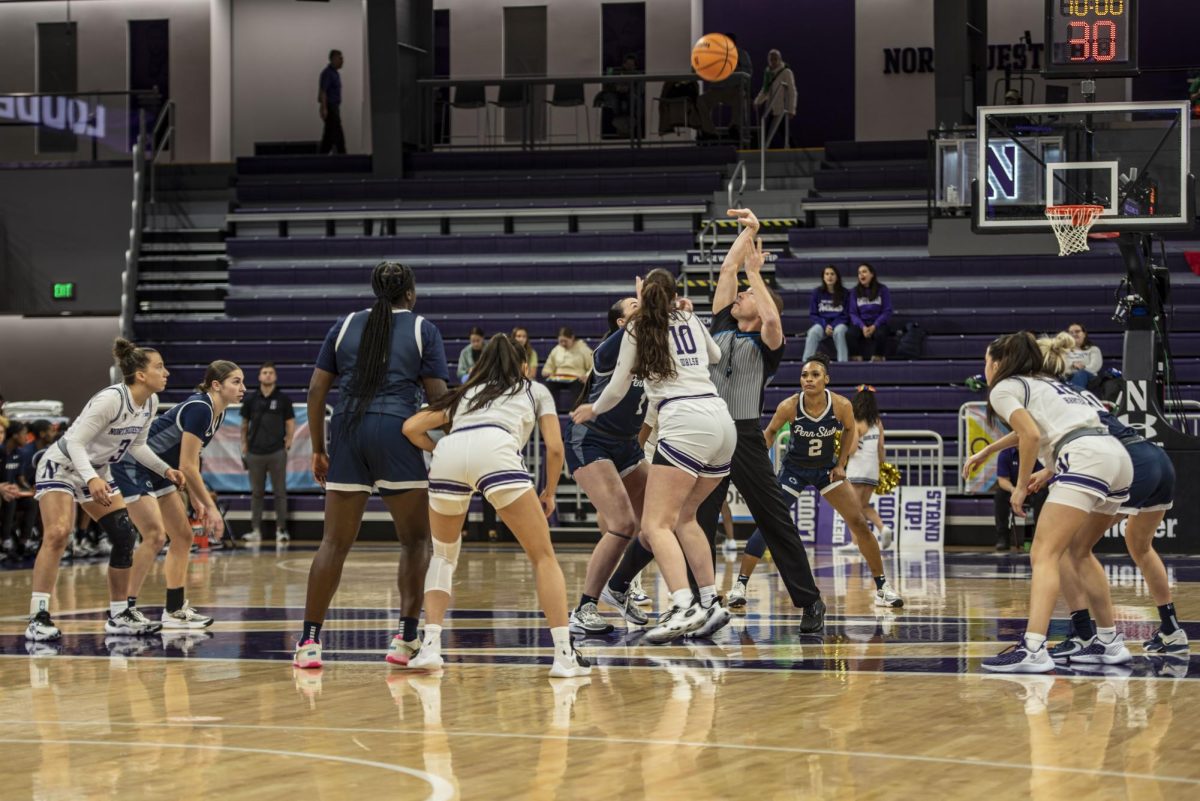 A Northwestern and Penn State player reach to gain control of the jump ball at the beginning of the game. 