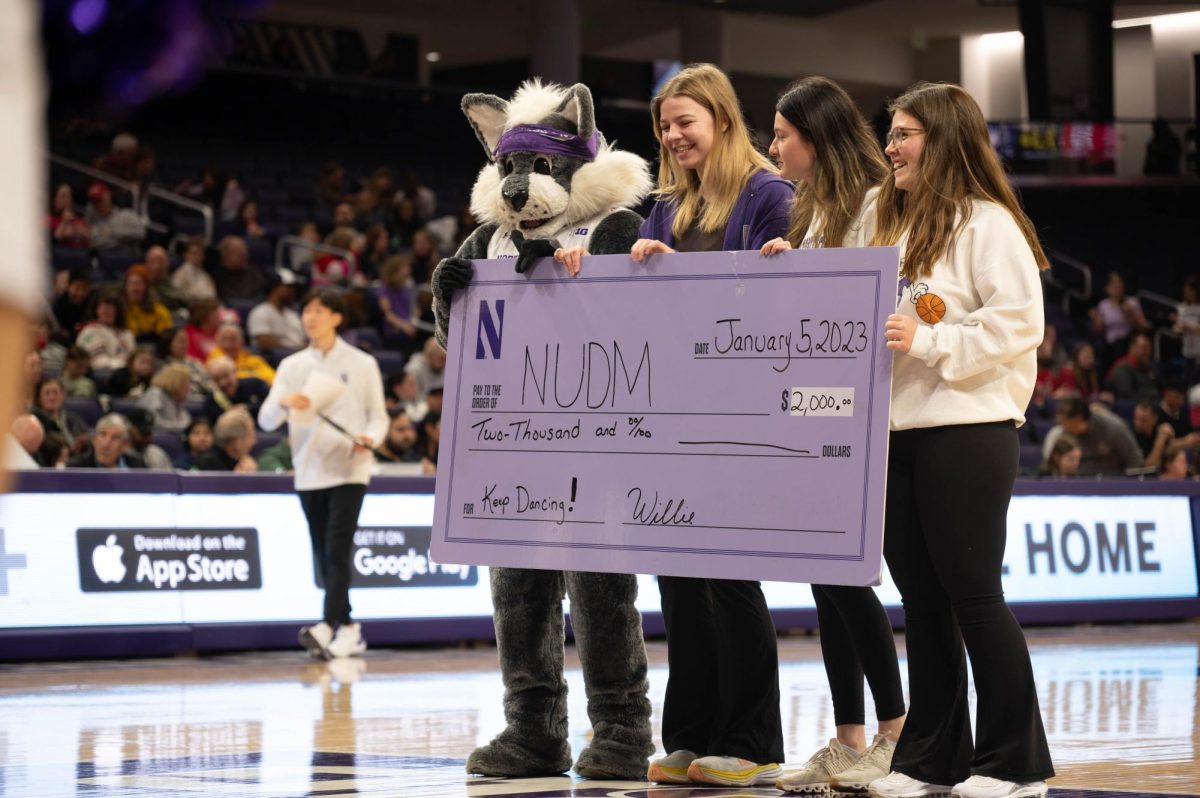 Three NUDM members accept a $2,000 check with Willie the Wildcat.