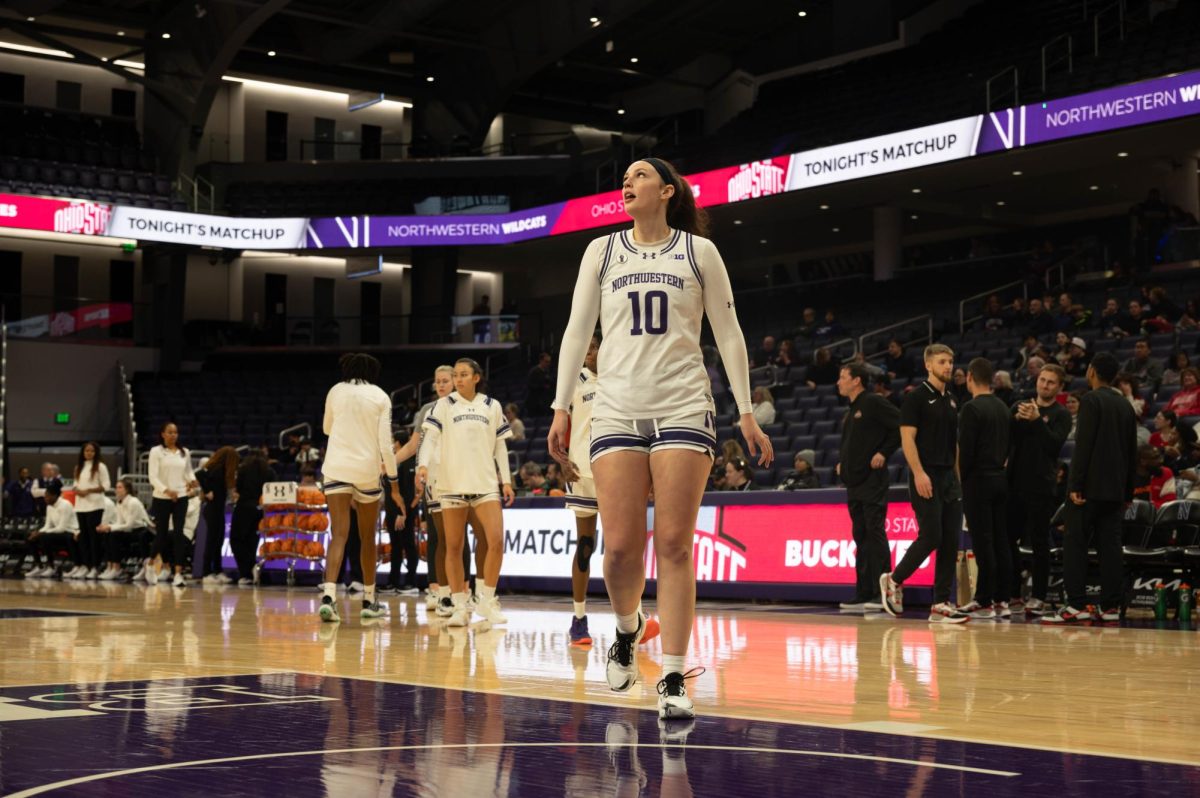 Basketball player Caileigh Walsh walks in a white uniform and watches a basketball shot.