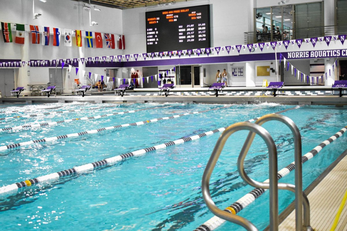 Northwestern’s empty swimming pool. A large sign in the back displays “Men 400 Free Relay” with players’ records below.