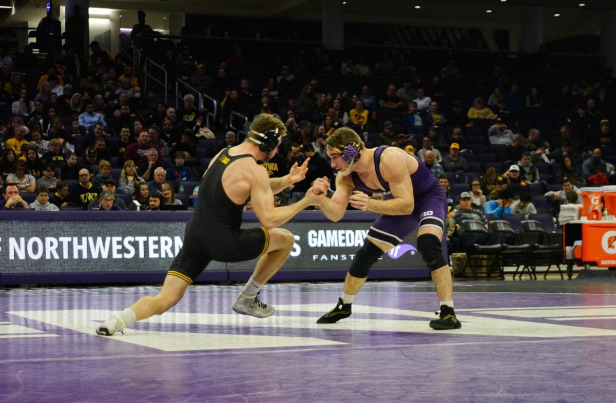 184-pounder Troy Fisher, wearing a purple singlet, loses wrist control to his opponent, wearing a black singlet.