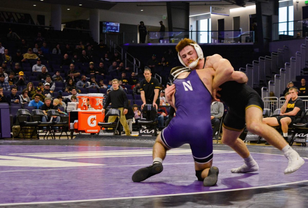 165-pounder Maxx Mayfield, wearing a purple singlet, attempts a takedown against his opponent, wearing a black singlet.