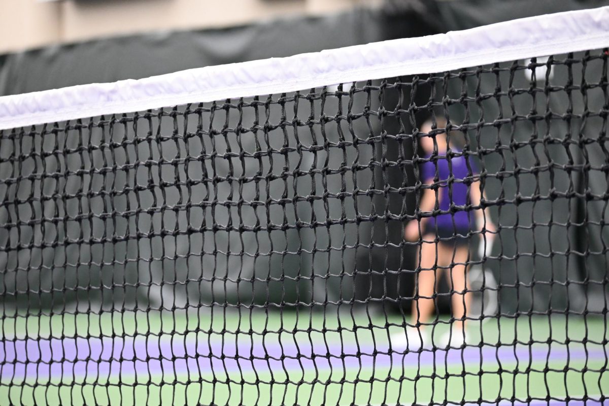 An NU Women’s Tennis player standing behind the net.
