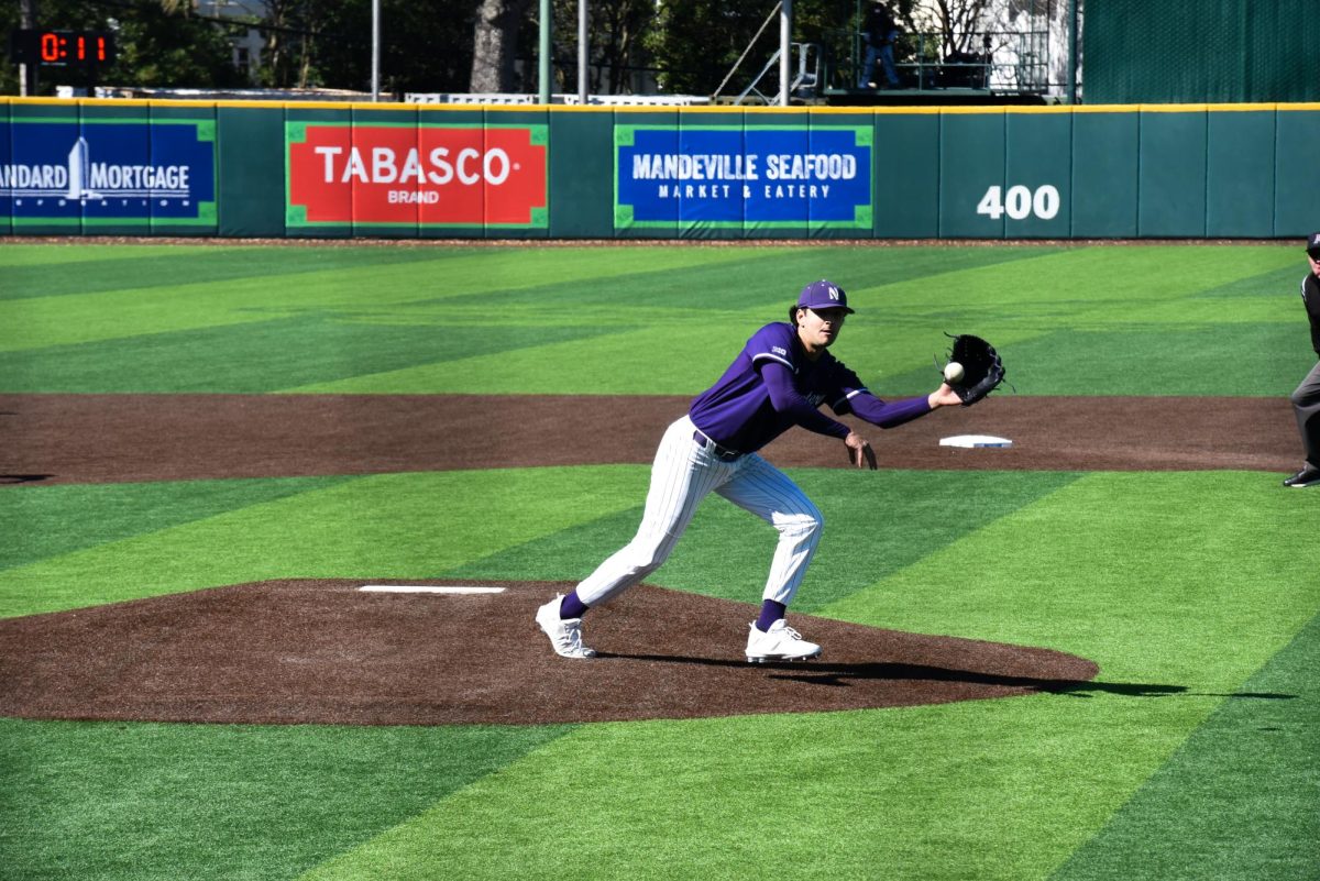 A Northwestern baseball player in a purple uniform catches a baseball.