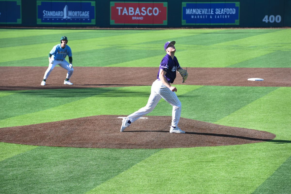 A Northwestern baseball player wearing purple looks for a baseball in the air.