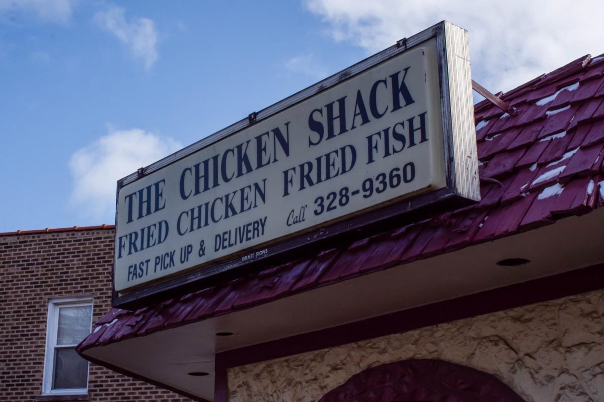 A sign on top of a building that reads “The Chicken Shack” in addition to providing a phone number and food options.