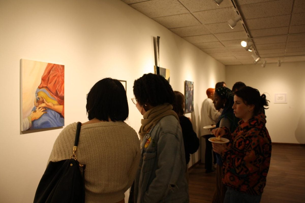 Students, community members and artists survey the different paintings, sculptures and collages in “Well Versed.” 