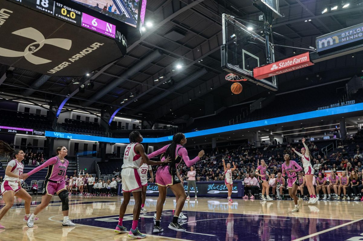 Northwestern’s Maggie Pina hits a three-pointer. Other players watch, appearing nervous.
