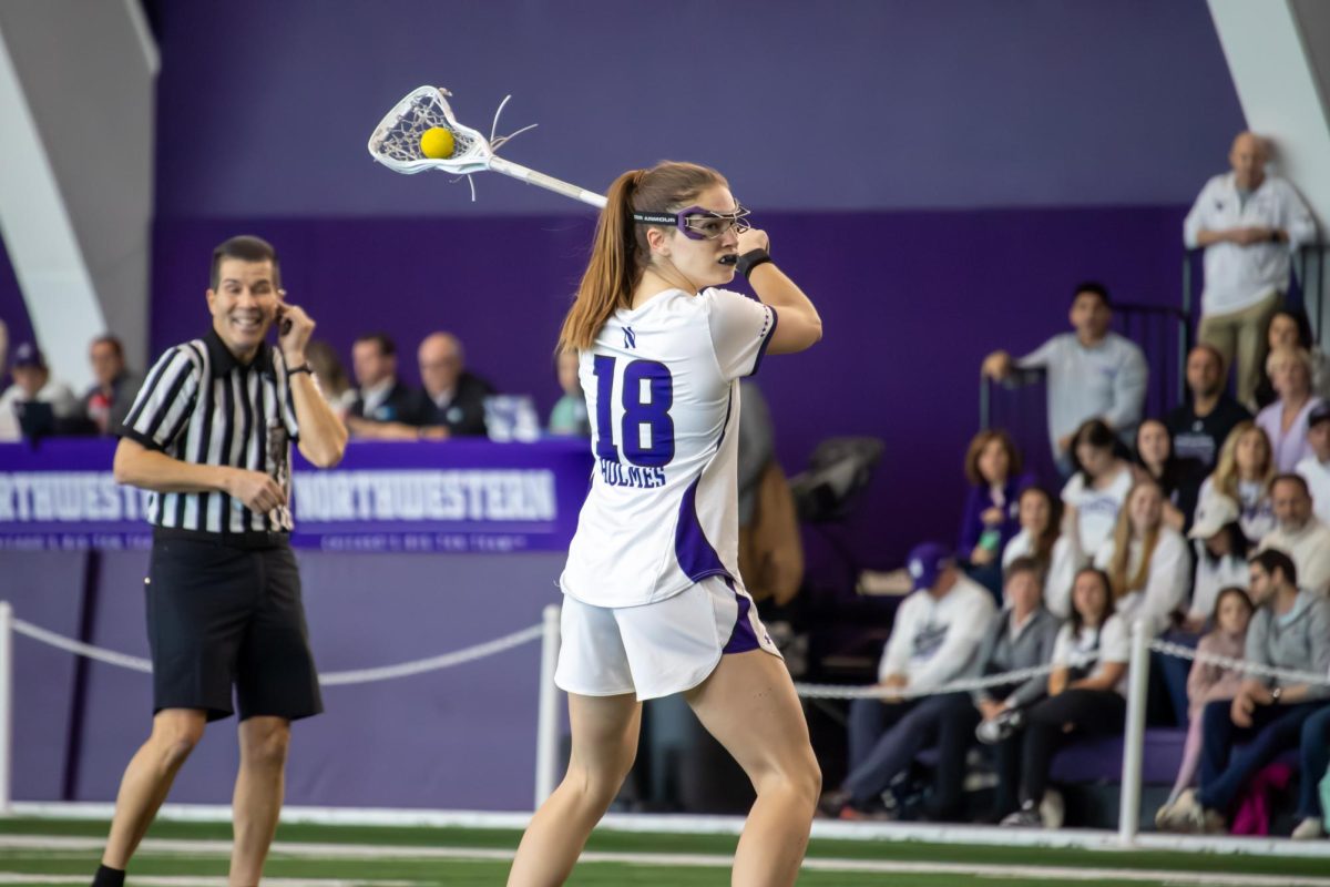 Senior attacker Leah Holmes holds the stick and ball overhead, aiming to score a goal.