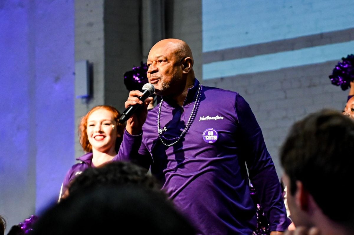 A former Northwestern basketball player, Billy McKinney speaks into a microphone, addressing the crowd.