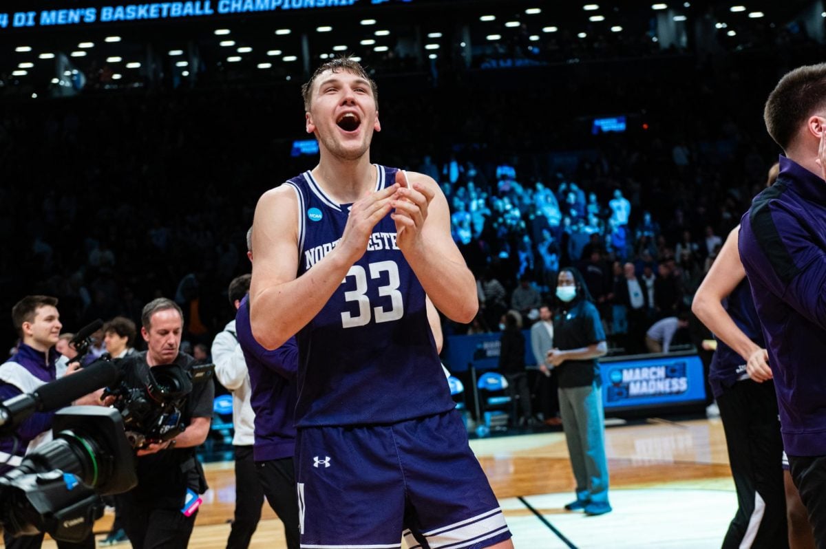 A basketball player in purple claps after a victory.