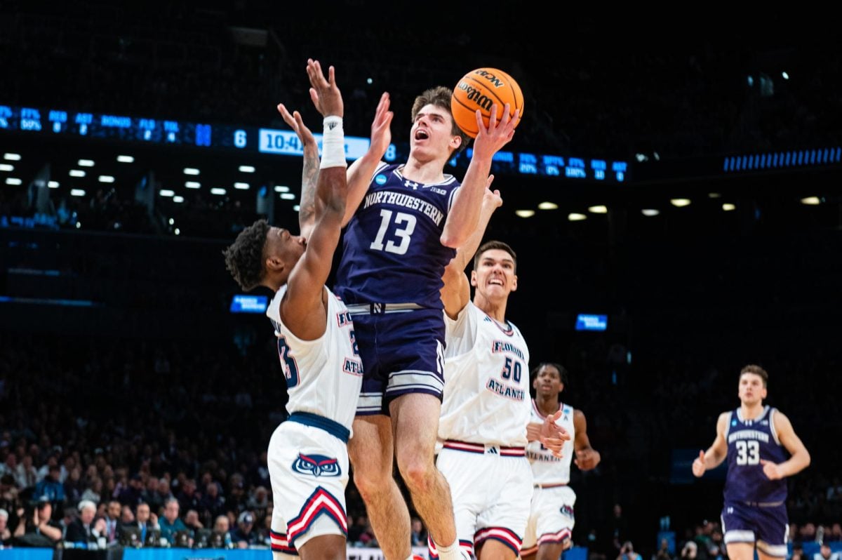 A basketball player in purple jumps to throw the ball into the basket.