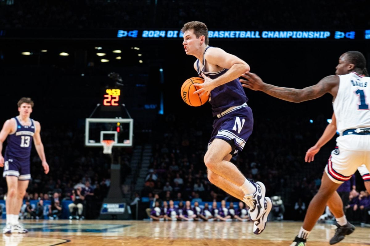 A basketball player in purple jumps to catch a ball.