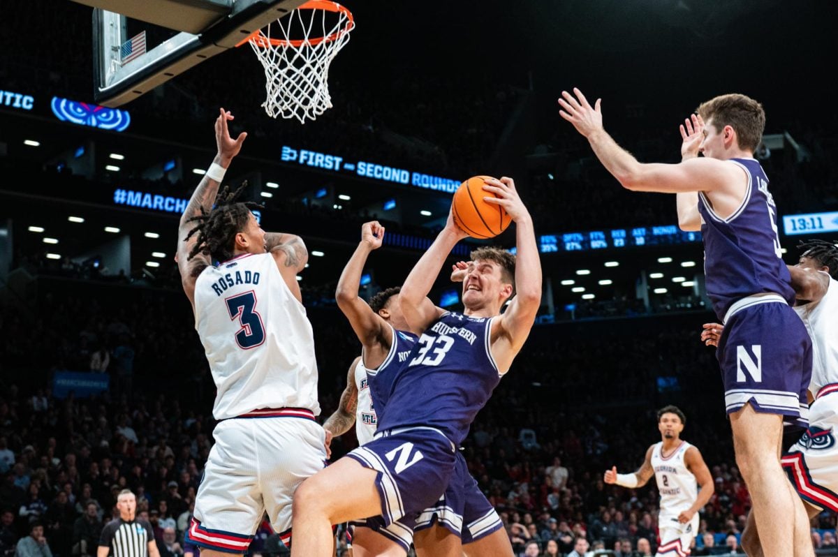 A basketball player in purple catches the ball after an attempt at the basket.