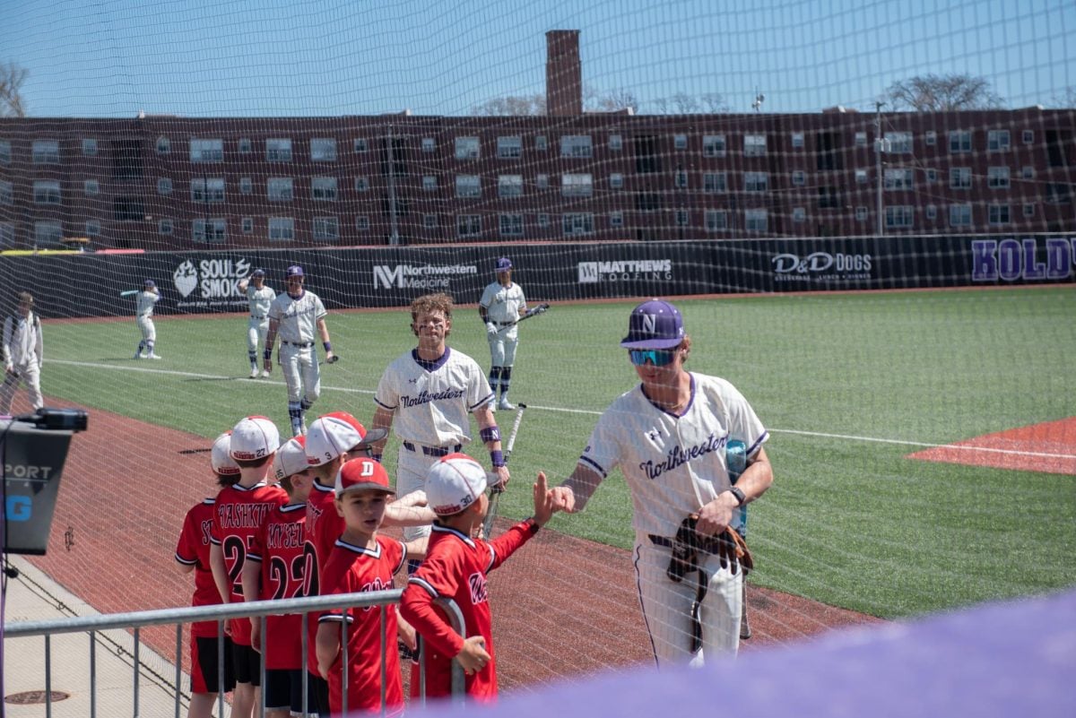 Northwestern players fist-bump little leaguers on their way into the dugout.