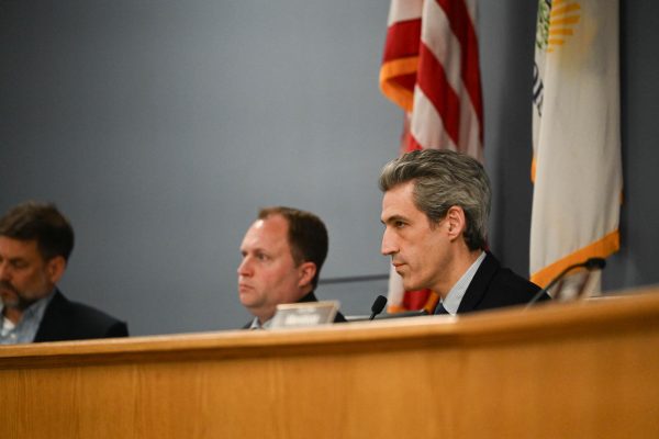 Daniel Biss, wearing a dark suit, sits at a dais.