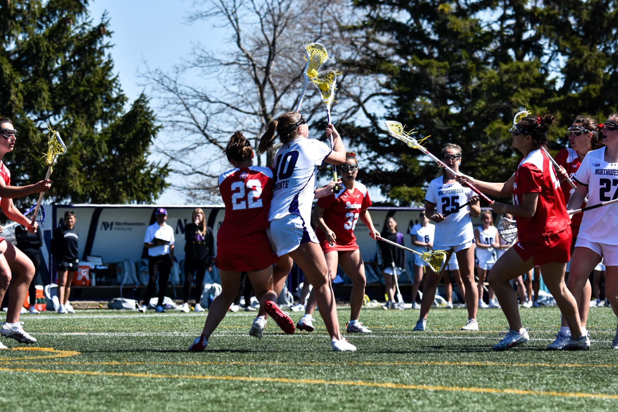 A Northwestern lacrosse player wearing white defends the ball from a player wearing red.